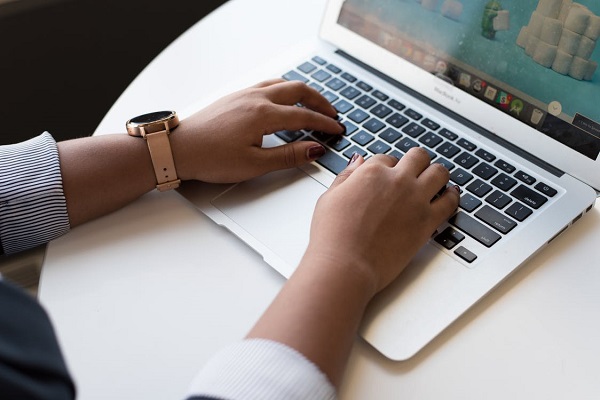 A set of hands at a laptop keyboard.
